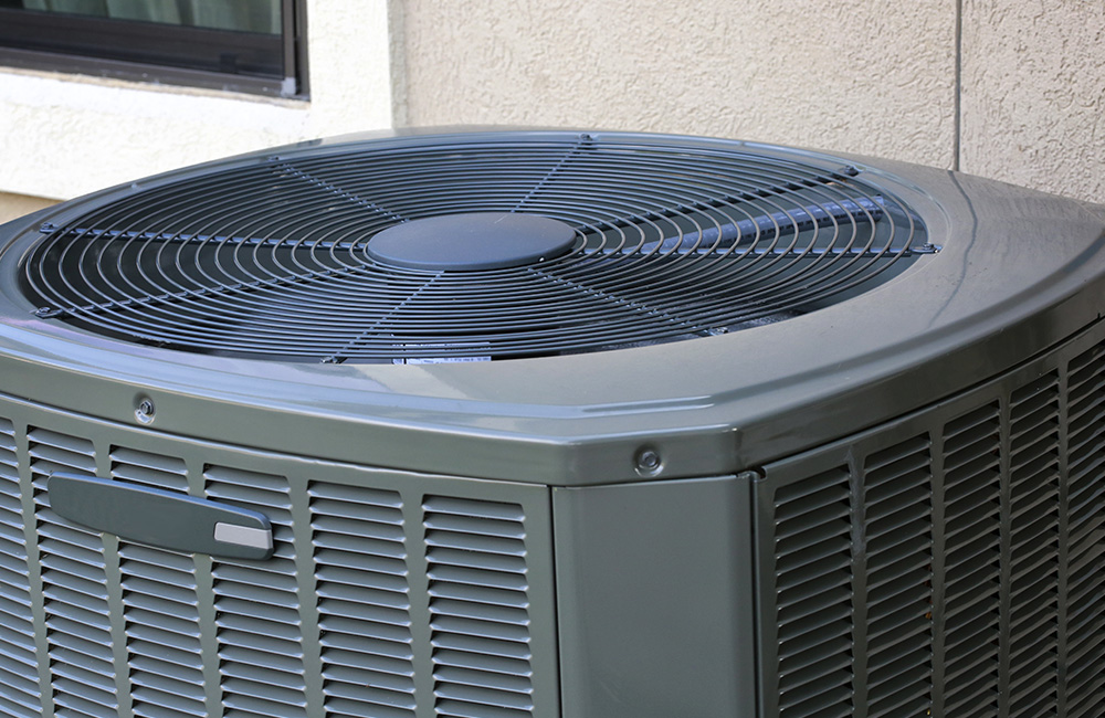 photo of a black outdoor AC unit used for central AC attached to a house
